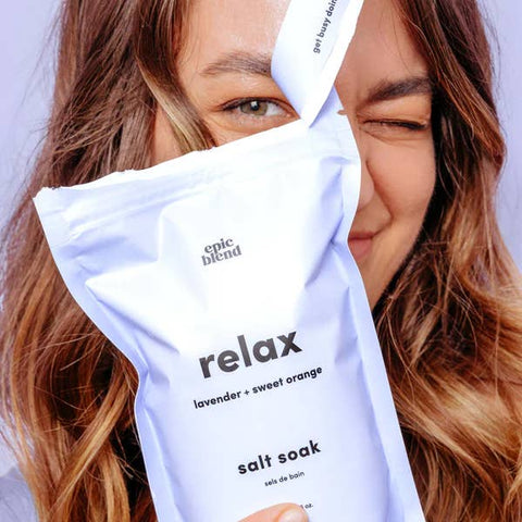 Woman holding a 'relax' salt soak package with visible branding