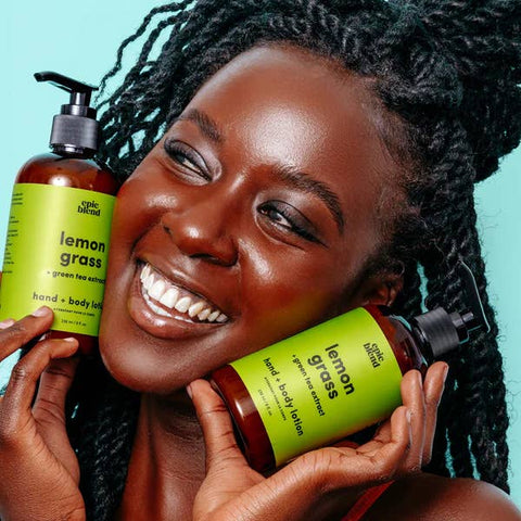 Woman holding two bottles of lemon grass hand and body lotion with a teal background