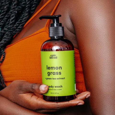 Hand holding a bottle of 'epic blend' lemon grass body wash with green label.